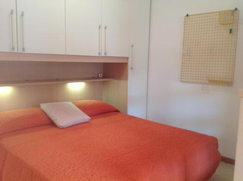 a bedroom with an orange bed and white cabinets at RESORT VILLAGE AQUA MARINA FAMILY - Daily Rooms Tidying - CocktailsBar- Pet Friendly - with Hypermarket - Delivery Restaurant-Pizzeria - Room Breakfast with supplement - Ultra Fast Wi-Fi - Play Area for children - Olympic Swimming Pool - Parking in Caorle
