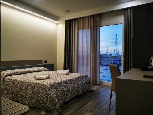 ヴィボ・バレンティア・マリーナにあるSARACENO HOTELのベッドと大きな窓が備わるホテルルームです。