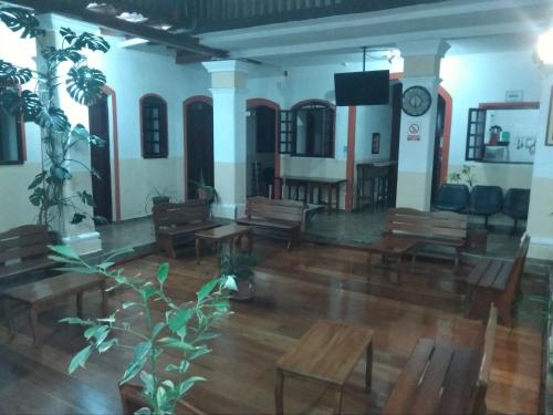 a large room with wooden tables and chairs and a clock at Hostal Buenos Aires in Quito