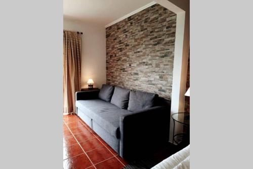 a living room with a couch and a brick wall at Casa da Fonte in Ginetes