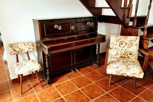 a piano and two chairs in a room at Casa da Fonte in Ginetes