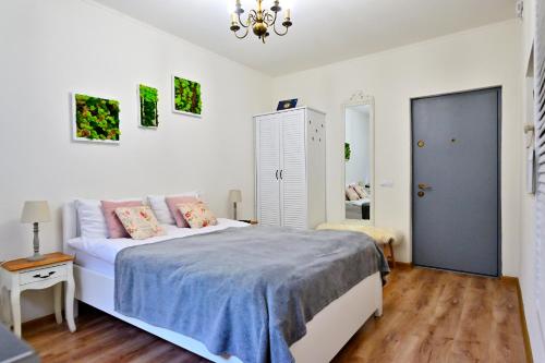 a white bedroom with a bed and a chandelier at Transilvania Apartment in Sibiu
