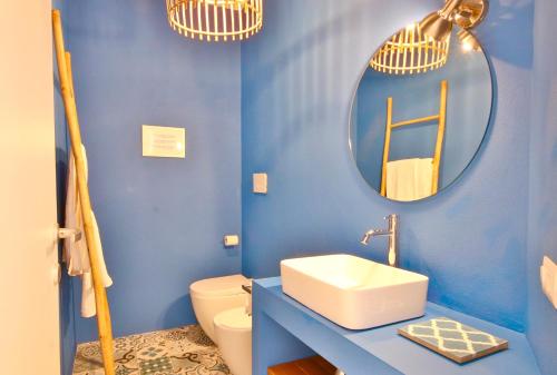 een blauwe badkamer met een wastafel en een spiegel bij LA VEDETTA dell’Eden by KlabHouse in Domus de Maria