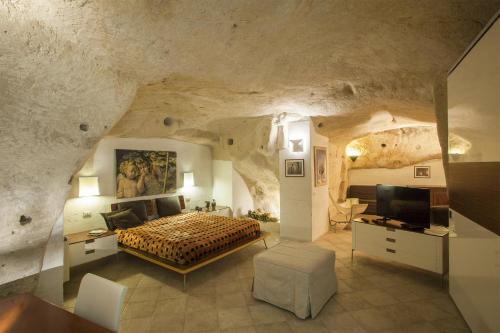una camera da letto in una grotta con un letto e una televisione di Residence San Pietro Barisano a Matera