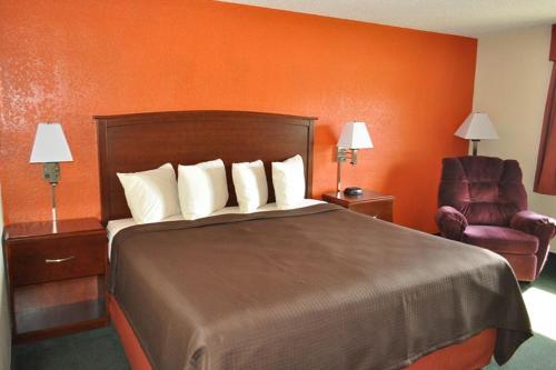 a hotel room with a bed and a chair at AmericInn by Wyndham Plymouth in Plymouth