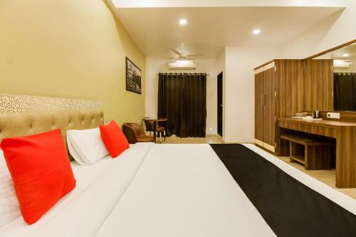 um quarto com uma cama grande e almofadas vermelhas em Hotel Om Inn - Talegaon Dabhade em Talegaon Dābhāde