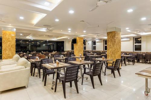 a restaurant with tables and chairs in a room at Hotel Om Inn - Talegaon Dabhade in Talegaon Dābhāde