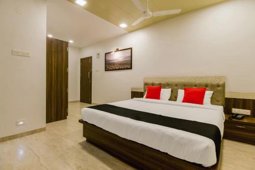 a bedroom with a large bed with red pillows at Hotel Om Inn - Talegaon Dabhade in Talegaon Dābhāde