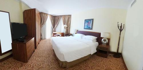 a bedroom with a large bed and a television at The Apartments in Jeddah