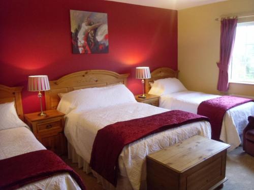a bedroom with three beds with red walls at Lake Avenue House in Ballyconnell