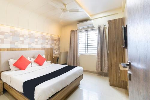 a bedroom with a bed with red pillows at Hotel Plaza Heights in Bangalore