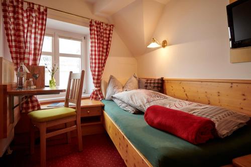 a bedroom with a bed with a chair and a desk at Hotel Krone in Schruns-Tschagguns
