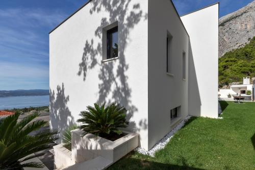 a white house with a plant in a yard at Villa Melody in Bast