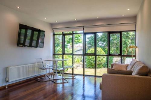 a living room with a couch and a glass table at Luxury Summerhouse Annexe in lush gardens in Fowey in Fowey