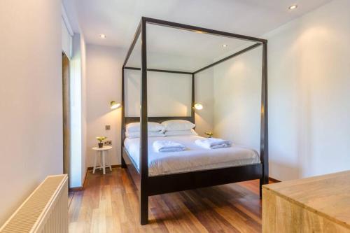um quarto com uma cama de dossel preta e um espelho em Luxury Summerhouse Annexe in lush gardens in Fowey em Fowey