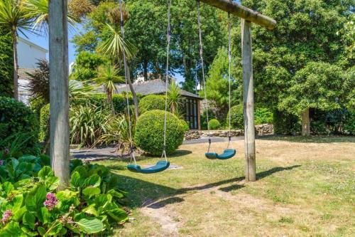 two swings in a yard with a house at Luxury Summerhouse Annexe in lush gardens in Fowey in Fowey