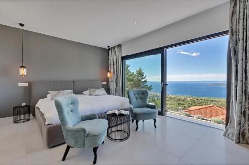 a bedroom with a bed and two chairs and a large window at Villa Melody in Bast