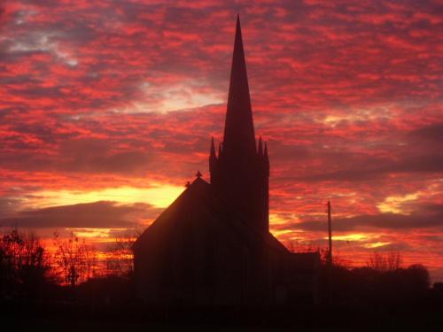 a silhouette of a church with a red sky at Lake Avenue House in Ballyconnell