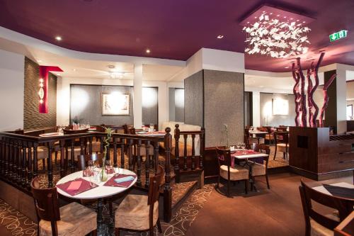 a restaurant with tables and chairs and a chandelier at Cit'Hotel le Challonge in Dinan