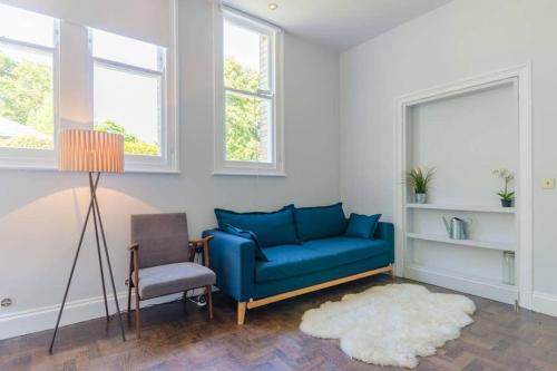 a living room with a blue couch and a chair at Classroom Flat Suite in a converted school in Fowey town centre in Fowey