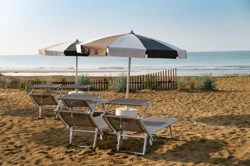 a group of chairs and umbrellas on a beach at Savoy Beach Hotel & Thermal Spa in Bibione