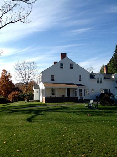 a large white house on a field of green grass at Stephen Clay Homestead Bed and Breakfast in Candia