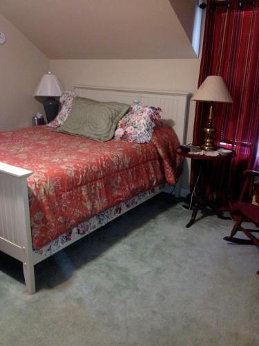 a bedroom with a bed and a table with a lamp at Stephen Clay Homestead Bed and Breakfast in Candia