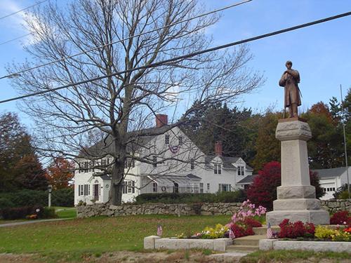 a statue of a man in front of a white house at Stephen Clay Homestead Bed and Breakfast in Candia