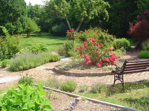 a park bench sitting in a garden with flowers at Stephen Clay Homestead Bed and Breakfast in Candia