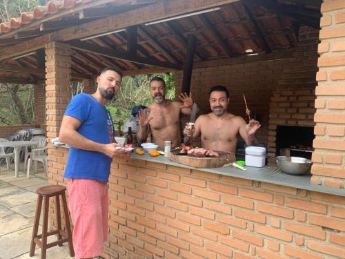 a group of men standing around a barbecue grill at Chales em Salesopolis - Recanto da Barra in Salesópolis