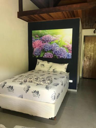 a bedroom with a bed with a painting on the wall at Chales em Salesopolis - Recanto da Barra in Salesópolis