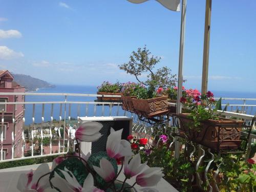 uma varanda com flores e vista para o oceano em DEPANDANCE CASA ANDREA em Taormina