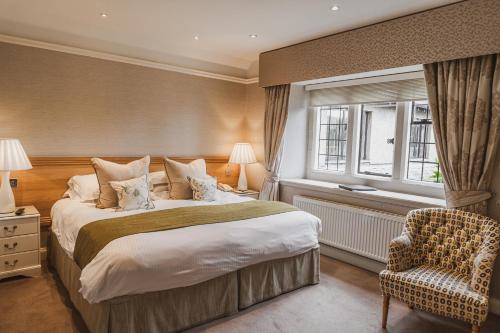 a bedroom with a bed and a chair and a window at Cragwood Country House Hotel in Windermere