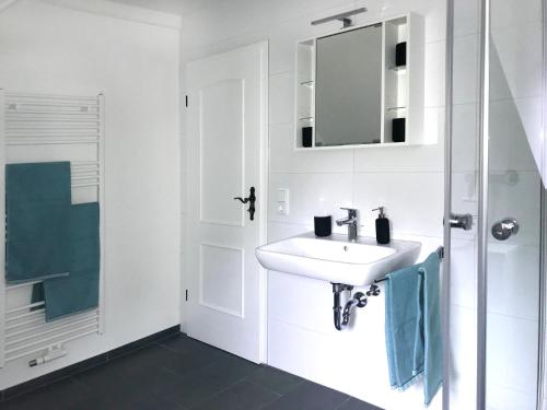 a white bathroom with a sink and a mirror at Altstadtperle Nideggen in Nideggen