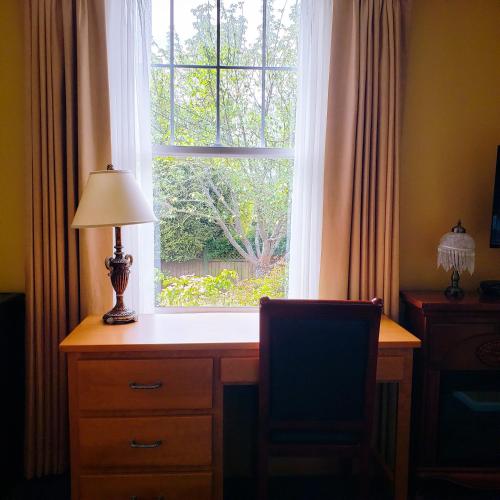 a desk with a lamp in front of a window at James Bay Inn Hotel, Suites & Cottage in Victoria
