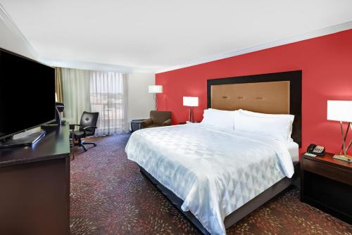 a hotel room with a large bed and a flat screen tv at Holiday Inn Tyler - Conference Center by IHG in Tyler