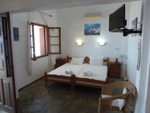 1 dormitorio con 1 cama y TV en Studios Milos Skopelos-Where the Sea Meets the Sky, en Skopelos Town