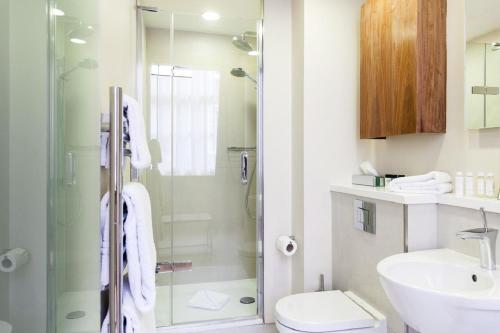 a bathroom with a shower and a toilet and a sink at Suffolk Lane by Blueprint Living in London