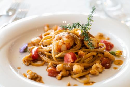 a white plate of pasta with shrimp and vegetables at Lino delle Fate Eco Resort in Bibione