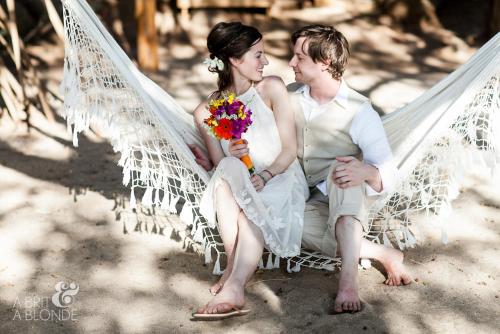 a bride and groom sitting on a white hammock at Sueño del Mar Beachfront Hotel in Tamarindo