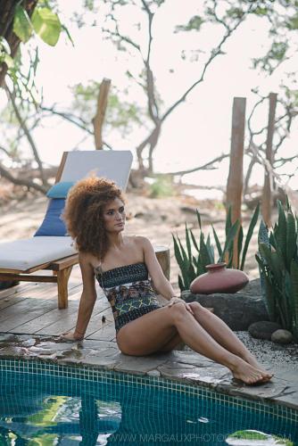 a woman in a bathing suit sitting next to a pool at Sueño del Mar Beachfront Hotel in Tamarindo