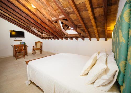 a bedroom with a white bed with a wooden ceiling at Bioma Boutique Hotel in Mompos