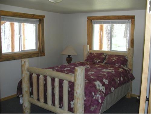 1 dormitorio con 1 cama de madera y 2 ventanas en Trails End Lodge, en Custer