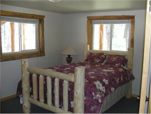 a bedroom with a wooden bed and two windows at Trails End Lodge in Custer