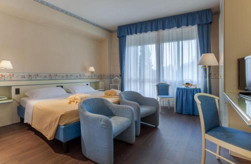 a hotel room with a bed and chairs and a television at Hotel Bristol Buja in Abano Terme