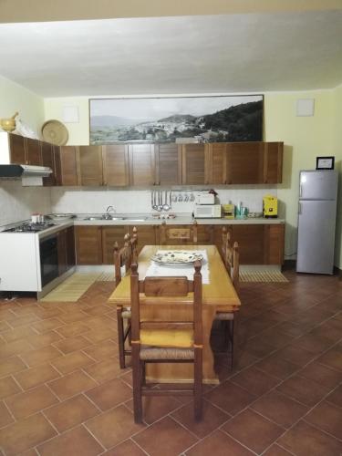 a kitchen with a wooden table and a refrigerator at Le Coste Affittacamere in San Lupo