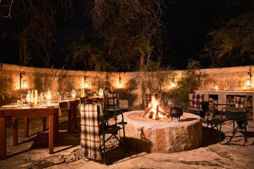 a fire pit in a yard with tables and chairs at Glen Harry Game Reserve in Graaff-Reinet
