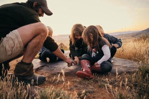 a group of children sitting on a path with a man at Glen Harry Game Reserve in Graaff-Reinet