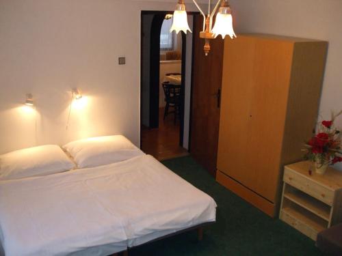 a bedroom with a white bed and a room with a table at Rekreacny dom Altwaldorf Vysoke Tatry in Stará Lesná