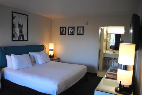 a bedroom with a white bed with two lamps and a window at Floridian Hotel in Homestead